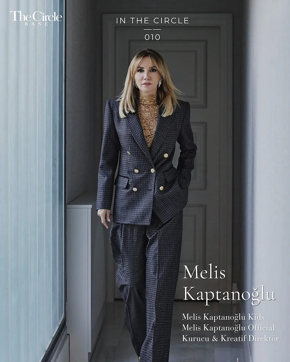 Melis Kaptanoğlu standing in a doorway in a navy pinstripe suit