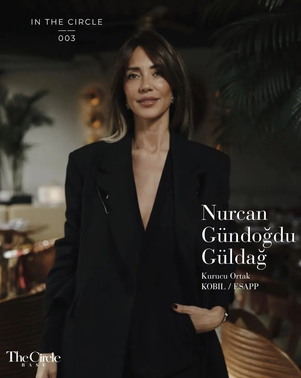 Nurcan Gündoğdu Güldağ in a black blazer, standing in a dimly lit restaurant
