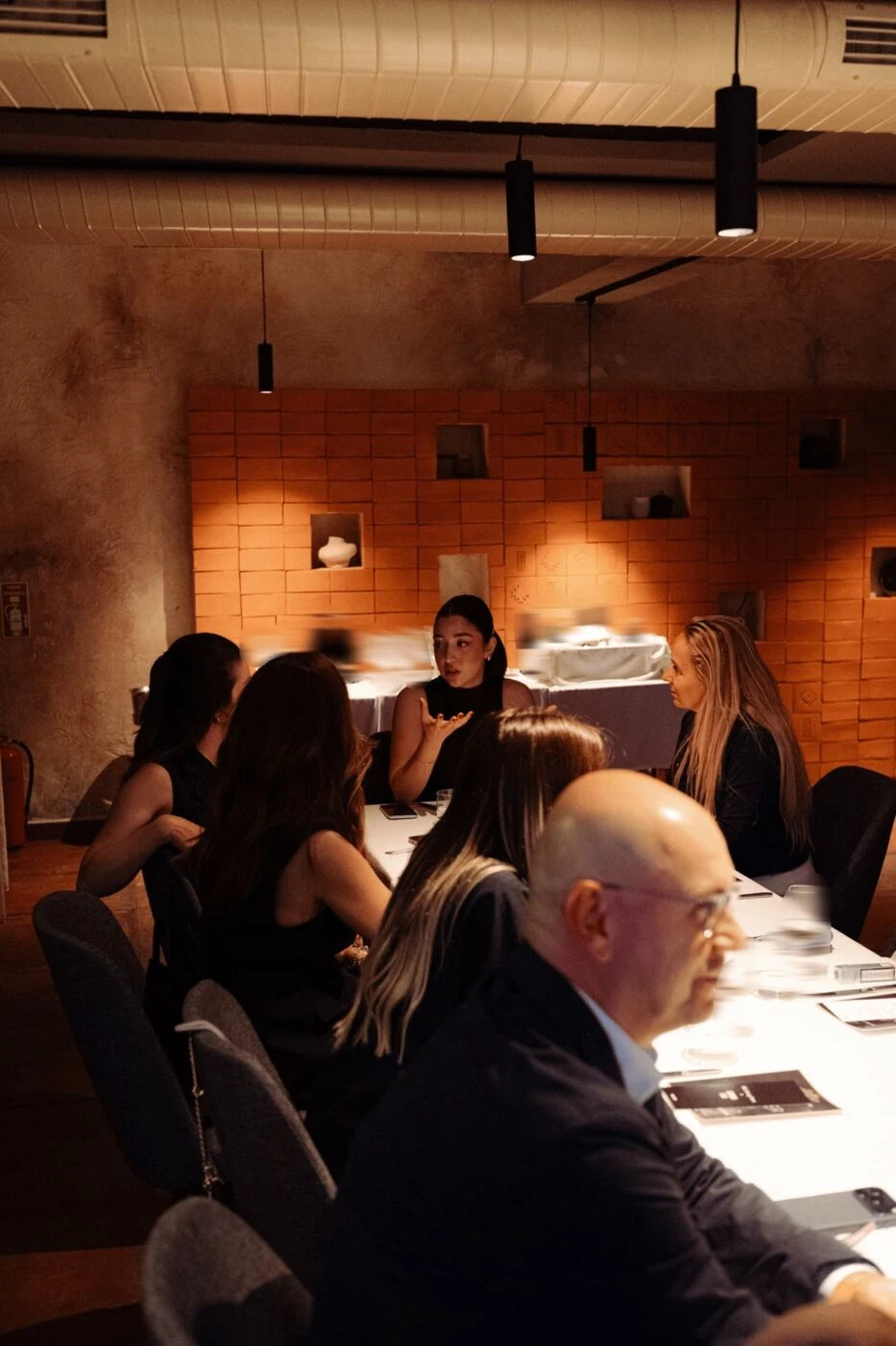The room in full — guests seated together under warm terracotta light