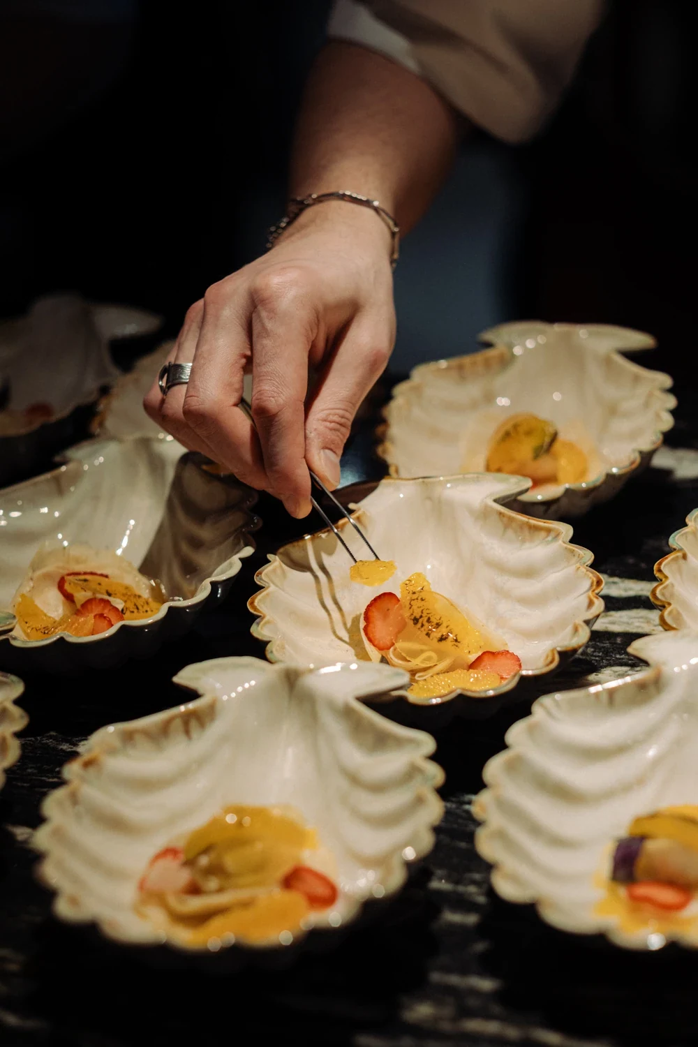 A chef's hand placing a garnish with tweezers