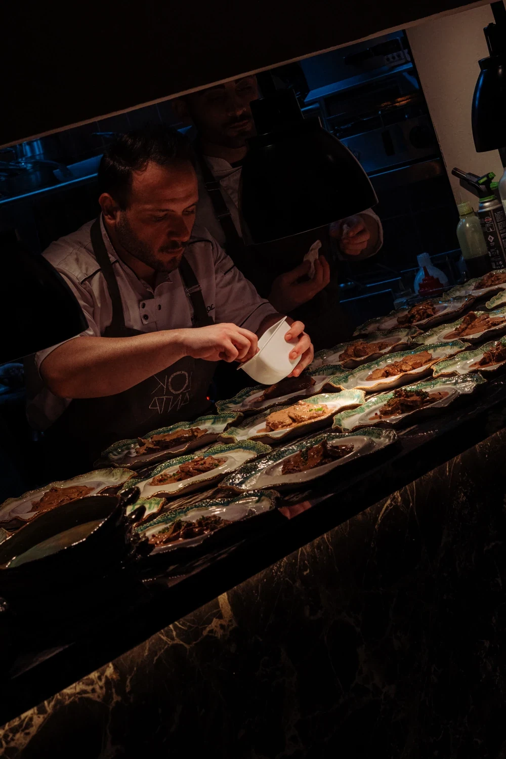 A chef plating along a dark marble counter