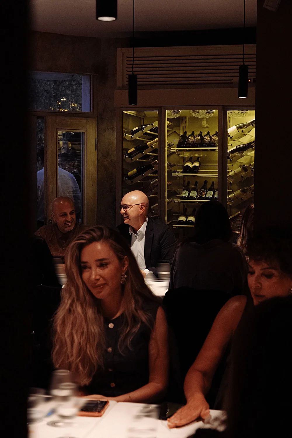 Guests gathered in front of a glowing wine cellar